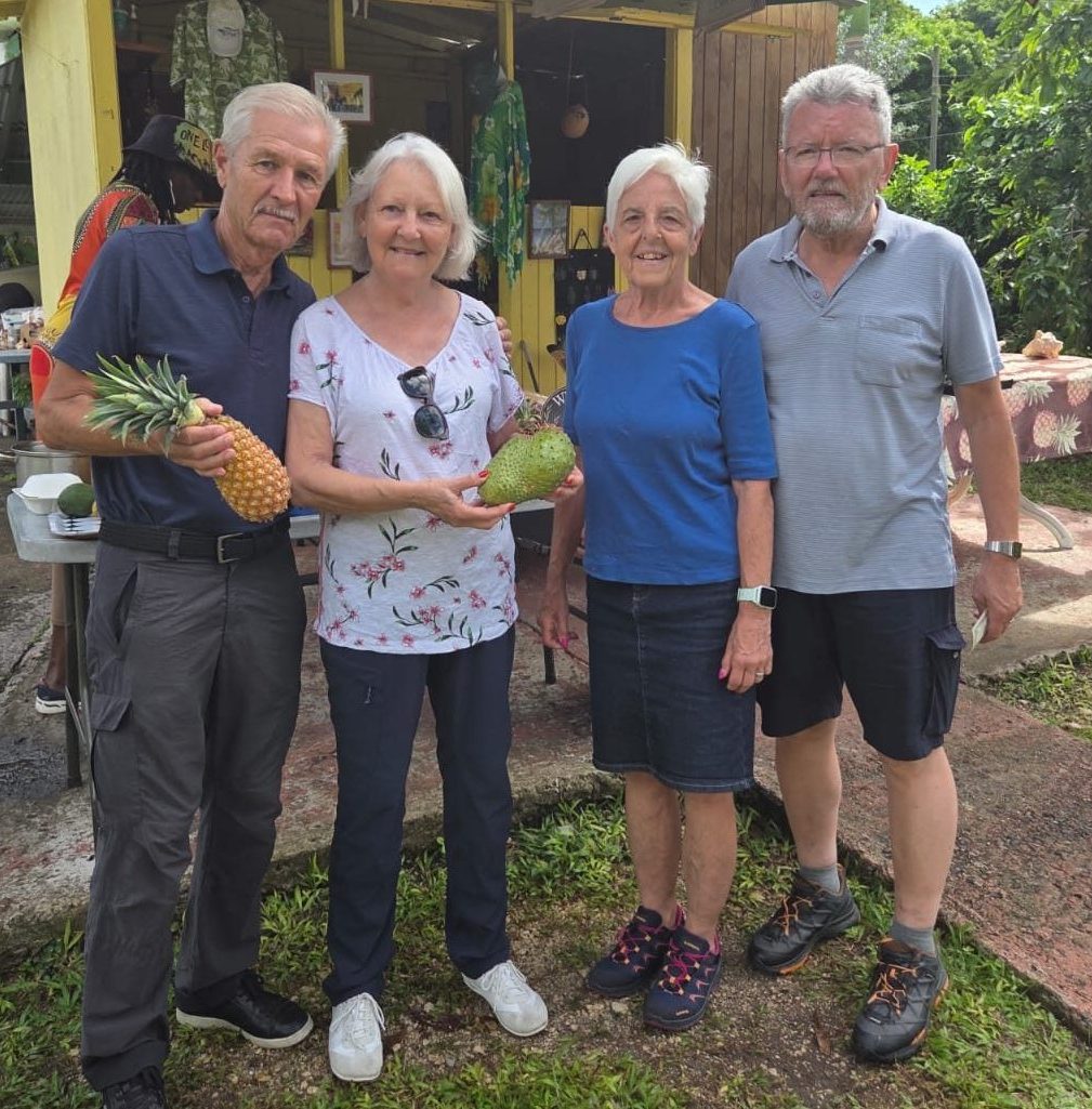​Happy tourists enjoying a private island sightseeing tour in Antigua with local fruits